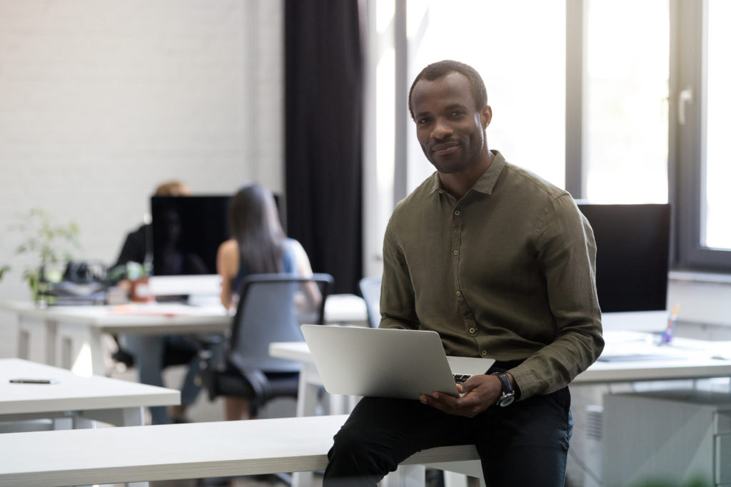 L’attribut alt de cette image est vide, son nom de fichier est smiling-happy-afro-american-businessman-sitting-his-desk-1024x683.jpg.